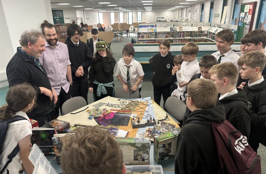 Members of Balerno High School Role Plaing Club standing round a table with the new games