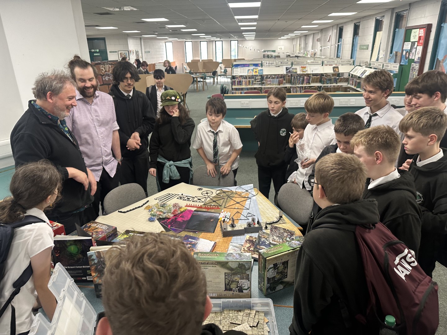 Members of Balerno High School Role Plaing Club standing round a table with the new games